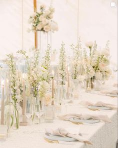 the table is set with white flowers and candles for an elegant wedding reception or special event