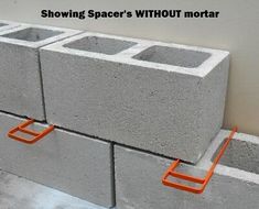 some concrete blocks are stacked together with orange handles on each side and the words showing space's without mortar