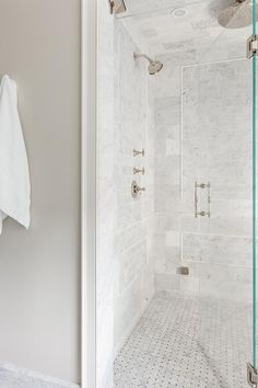 a walk in shower sitting next to a white tiled wall and floor covered in tile