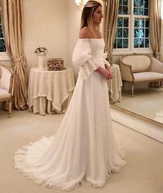 a woman in a white wedding dress looking at herself in the mirror