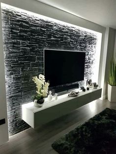 a room with a large television on the wall and plants in vases next to it