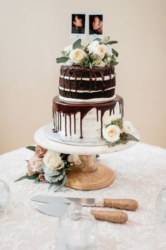 a wedding cake with flowers and chocolate drizzle on top is sitting on a table