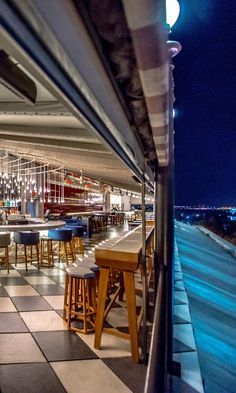 an outdoor restaurant with checkered tile flooring and bar stools at the end