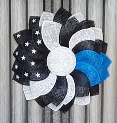 a black, white and blue flower with stars on the center is hanging from a wooden fence