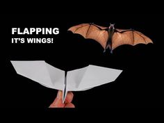 a hand holding an origami bat with the words flapping it's wings