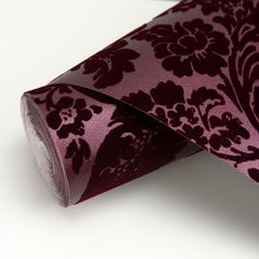 a close up of a purple tie on a white surface with black and red flowers