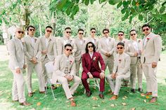 a group of men in suits and sunglasses posing for a photo together on the grass