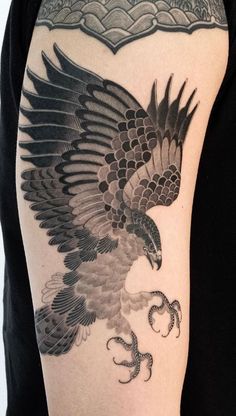 an eagle tattoo on the back of a woman's arm, with black and grey ink