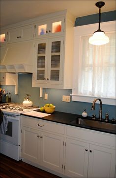 a kitchen with white cabinets and black counter tops in front of a stove top oven