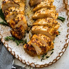 sliced chicken on a plate with herbs and seasoning sprinkled around the edges