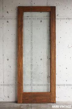 an empty room with a wooden door and concrete wall behind it, in front of a white brick wall