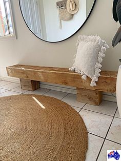 a wooden bench sitting in front of a round mirror