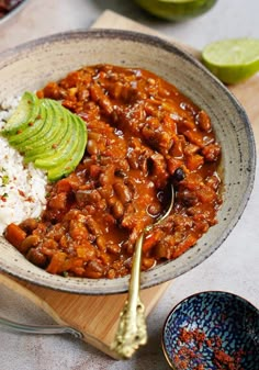 a bowl filled with rice, beans and avocado on top of a wooden cutting board