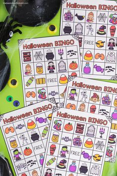 three halloween bingo game cards sitting on top of a green table