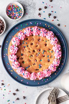 a cookie cake with pink frosting and sprinkles on a blue plate