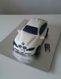 a cake shaped like a bmw car with a cell phone on the table next to it