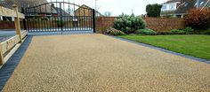 a gravel driveway with a wooden bench in the middle