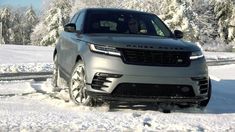 a silver range rover driving through the snow