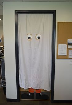 an open door with two fake eyes on it and a white sheet covering the doorway