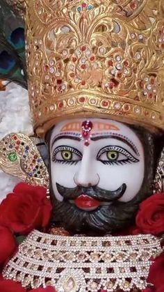 a close up of a statue of a person wearing a crown with roses in front of it