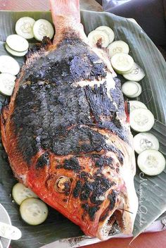 a large fish is on a plate with cucumbers