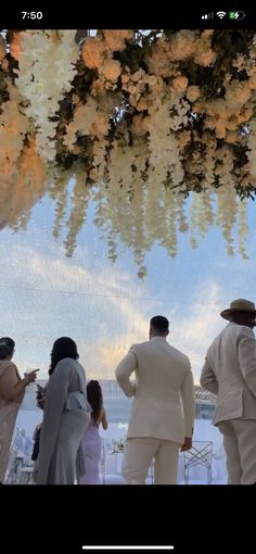 a group of people that are standing under some flowers