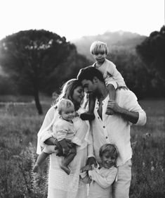 a black and white photo of a family posing in a field with their two children