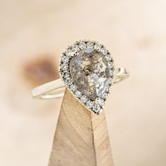 a pear shaped diamond ring on top of a wooden stand