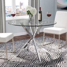 a glass table with two white chairs and a bottle of wine on top of it