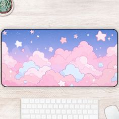 a computer mouse pad with pink clouds and stars on the surface next to a keyboard