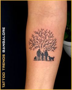 a family tree tattoo on the left arm with two people and a dog under it