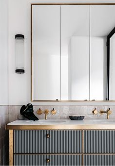 a bathroom vanity with two sinks and large mirror above it in front of a white wall