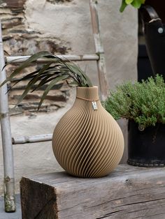 a brown vase sitting on top of a wooden table next to two potted plants