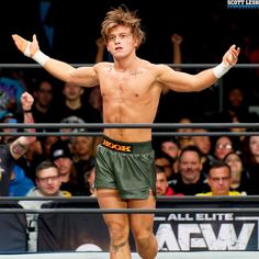 a shirtless man standing on top of a wrestling ring holding his arms out in the air