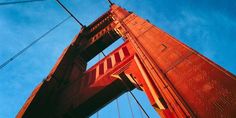 the top of a tall red bridge against a blue sky