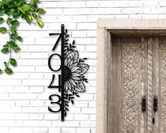 a large metal clock mounted to the side of a white brick wall next to a wooden door