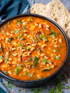 a bowl filled with beans and greens next to bread