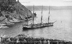 an old black and white photo of a boat in the water near a rocky shore