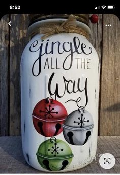 a painted mason jar that says,'jingle all the way'with three ornaments on it