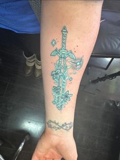 a person with a tattoo on their arm holding a cross in the palm of their hand