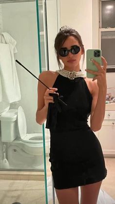 a woman taking a selfie in front of a mirror with her cell phone and wearing sunglasses