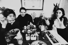 black and white photograph of four people sitting at a table with food in front of them