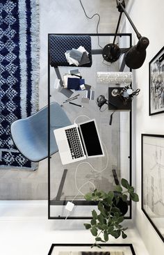 a laptop computer sitting on top of a glass table next to a plant and pictures