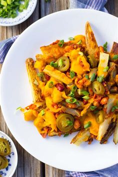 a white plate topped with french fries covered in cheese and toppings on top of a wooden table