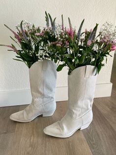 two white cowboy boots with flowers in them