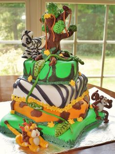 a three tiered cake decorated with animals and trees