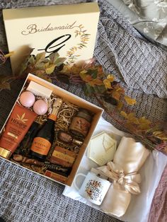 an open gift box on top of a bed next to some bottles and other items