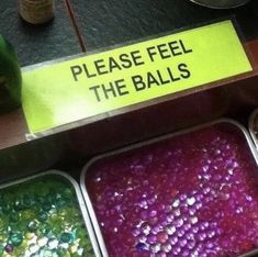 three trays filled with different colored beads next to a sign that says please feel the balls