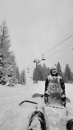 a snowboarder sitting in the snow next to a ski lift