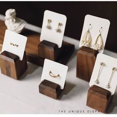 five pairs of earrings are on display in wooden stands with earring hooks and pearls